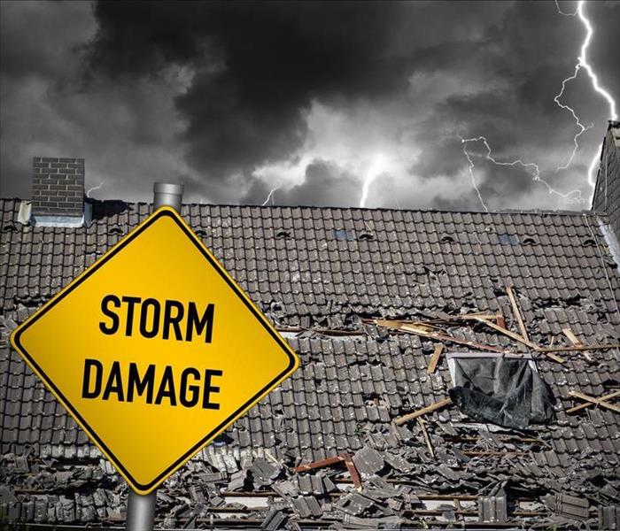 A damaged roof from a thunderstorm with a sign that spells Storm Damage